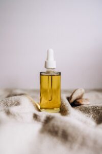 glass serum bottle with yellow liquid on beige woven fabric